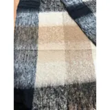 Bufanda rectangular de tejido grueso con diseño de cuadros en tonos azul, naranja, gris y beige, terminada con flecos en los extremos.