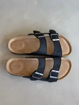 Sandalias negras con dos tiras anchas ajustables con hebillas metálicas plateadas.