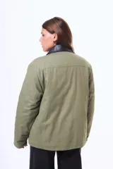 Campera de gabardina color verde militar con cuello de cuero sintético negro, cierre frontal con botones metálicos y bolsillos frontales con solapa.