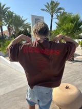 Remera celeste de corte holgado con estampado en rojo en la espalda con el texto "ittaistars", "European Tour by Ittai Stars Company" y el logo de la marca.