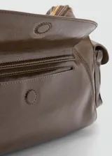 Bolso tipo bandolera de poliuretano en color marrón con acabado brillante, diseño estructurado con múltiples bolsillos externos con cierre y herrajes metálicos dorados.