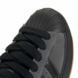 Championes Adidas Superstar ST de estilo urbano, confeccionados en gamuza gris con las icónicas tres tiras laterales en negro. Presentan la clásica puntera de goma, cordones negros y una suela de goma con base color caramelo.
