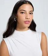 Top sin mangas negro, ajustado al cuerpo, con cuello alto y sutiles drapeados laterales.