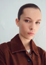 Chaqueta de cuero de cabra color marrón, con cuello clásico, cierre frontal de botones y diseño corto.