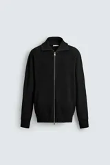 Chaqueta de punto con textura acanalada, cuello subido y cierre frontal completo con cremallera metálica. Presenta un corte relajado y acabados en rib en puños y ruedo.