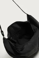 Bolso de hombro tipo hobo de nylon negro, con diseño curvo y asa ajustable. Cuenta con compartimento principal con cierre de cremallera y bolsillo interior con cremallera.
