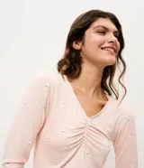 Blusa de pijama de manga larga confeccionada en viscolycra, con escote en V y detalle de frunce central con lazo. Presenta un estampado sutil de perritos sobre una base de color rosado.