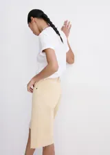 Bermuda de denim color amarillo pastel, de tiro bajo, corte recto y diseño de cinco bolsillos con cierre de botón y cremallera, y terminaciones deshilachadas.