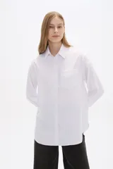 Camisa blanca de poliéster, corte holgado, con cuello camisero y cierre frontal con botones.