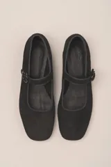 Zapato plano estilo Mary Jane de cuero negro, con punta fina y tira ajustable con hebilla sobre el empeine.
