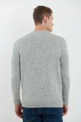 Sweater de tejido de punto color beige claro, con diseño de trenzas (aranes) en el frente y mangas de punto liso. Tiene cuello redondo.