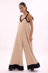 Mono palazzo color beige con terminaciones en negro, escote en V y tirantes anchos.