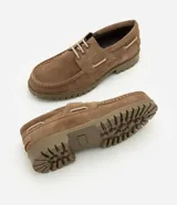 Zapato estilo náutico para hombre, confeccionado en cuero gamuza color marrón. Presenta diseño liso con puntera redondeada, costura aparente en la capellada, cordones bicolor y suela tractorada engomada.