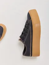 Championes de lona negra con plataforma y puntera de goma marrón, cordones negros y costuras en contraste.