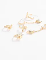 Set de caravanas doradas que incluye aros pequeños con forma de estrella, aros con dije de cruz, y aros con dije de corazón con cristal y cadena colgante.