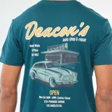 Camiseta de cuello redondo y manga corta en color azul petróleo, con estampado gráfico pequeño en el pecho que incluye el texto 'Deacon's'.