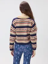Campera de punto estampada de corte holgado, con cierre metálico frontal y cuello de corderito sintético en color tostado. Presenta un diseño de franjas horizontales con patrones geométricos en tonos bordó, mostaza, marrón y beige.