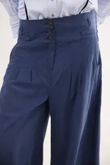 Pantalón de tiro alto en color azul, con cierre frontal de tres botones, pinzas en la cintura y corte holgado.