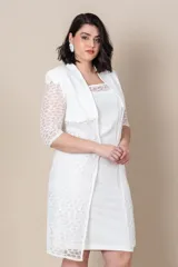 Vestido blanco de piqué con encaje en el escote, corte recto y largo a la rodilla. Incluye una túnica larga de la misma tela con tajos laterales y encaje al tono.