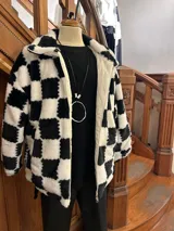 Campera de poliéster símil piel, con estampado a cuadros blancos y negros, cierre frontal y bolsillos laterales.