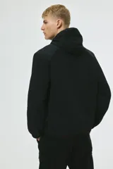 Campera rompevientos negra de nylon repelente al agua, con capucha ajustable, cierre frontal, bolsillos laterales y puños elásticos.