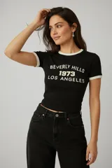 Remera de algodón con elastano, de corte ajustado y manga corta. Presenta un diseño tipo ringer con cuello y bordes de mangas en color blanco, y estampa frontal con texto en color blanco.