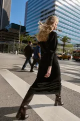Vestido midi de punto en color negro, con cuello barco y mangas largas con sisa ancha. Presenta una cintura entallada con un cinturón fino incorporado con hebilla metálica dorada.