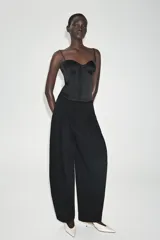 Top de satén negro estilo corsetero, con escote corazón, tirantes finos ajustables y cierre frontal con ganchos metálicos.