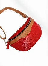 Riñonera roja con textura símil reptil y detalles en cuero color suela. Incluye doble correa: una de cuero color suela y otra de tela.