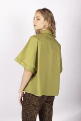 Camisa color ladrillo de corte holgado, con cuello camisero, mangas cortas con dobladillo y costuras a contratono.