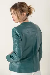 Campera de cuero ovino italiano color verde azulado, con cuello mao, cierre frontal con broches ocultos, bolsillos laterales y detalle de capitoneado en puños y bolsillos.