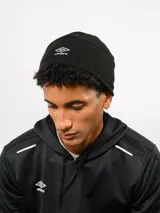 Gorro tipo beanie de Umbro, confeccionado en tejido polar negro, con el logo de la marca bordado en blanco en la parte frontal.