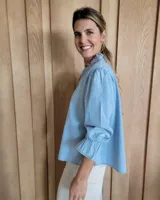 Blusa de algodón con cuello mao y volados, mangas largas con puños elásticos y corte holgado.