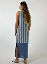 Vestido largo tejido a crochet, con rayas verticales color naranja y beige, sin mangas y con aberturas laterales.