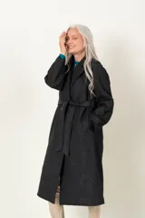 Trench negro capitoneado con bordado floral, corte clásico, cuello solapa, cierre cruzado con broches, lazo para ajustar en la cintura y bolsillos laterales.