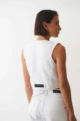 Chaleco denim con botones plateados en la parte delantera y bolsillos simulados.