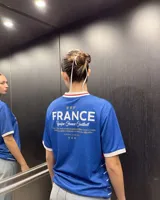 Remera de fútbol inspirada en la selección de Francia, de color azul con franjas horizontales blancas y una franja roja en el pecho, cuello en V blanco y dorsal 10 en la parte frontal.