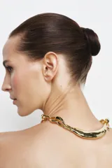 Collar de metal dorado compuesto por una cadena de eslabones grandes y ovalados, con una pieza central curva y texturizada que simula un metal martillado o fluido.