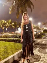 Vestido tejido en lurex color plateado, con diseño geométrico en cuero en el frente y flecos en el ruedo. Breteles finos de cuero con tientos plateados.