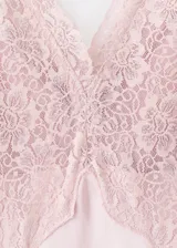 Vestido largo de estilo lencero en tejido satinado color rosado. Presenta escote en pico con detalle de encaje en el pecho y en el bajo, tirantes anchos ajustables y cierre de cremallera lateral.