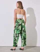 Pantalón largo de seda fría estampada con hojas de palmera en tonos verdes y blancos sobre fondo negro. Tiene pretina ancha elastizada.