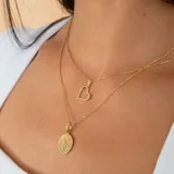 Conjunto compuesto por una cadena fina de eslabones y un dije circular con la imagen de San Benito, ambos realizados en oro 18k.