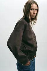 Campera bomber color beige, de cuello redondo y manga larga. Tiene bolsillos delanteros y bajo acabado en elástico. Cierre frontal con cremallera.