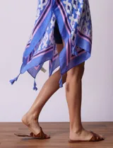 Kimono tejido con estampado abstracto en tonos azules, blancos y violetas. Tiene terminación de ruedo con borlas.