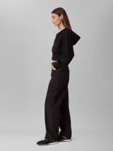 Buzo cropped con capucha y cierre frontal completo, confeccionado en punto milano. Presenta mangas largas con puños acanalados y dobladillo inferior también acanalado, ofreciendo una silueta estructurada y moderna.