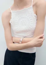 Top blanco sin mangas, con tirantes finos, cuello halter y detalle de aplique de crochet en la parte frontal. Diseño entallado.