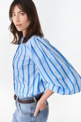 Camisa de manga larga abullonada con diseño a rayas verticales celestes y azules, cuello mao y cierre frontal con botones ocultos.