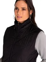 Chaleco acolchado de color negro con diseño de rombos, cierre frontal completo y bolsillos laterales con cierre. Presenta cuello alto y es resistente al agua y al viento.