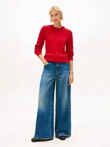 Sweater de punto con diseño de trenzas, cuello redondo y detalle de botones dorados en el hombro. Presenta terminaciones acanaladas en puños y dobladillo, con el logo de la marca bordado en el pecho.