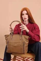 Cartera tipo tote de diseño estructurado en símil cuero, con doble asa rígida y correa regulable. Presenta múltiples bolsillos frontales con cierre y solapa, ofreciendo un estilo versátil y espacioso.